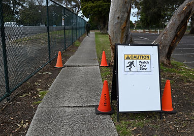 Sign warning of trip hazard on sidewalk.