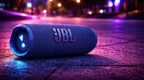 Caixa de som JBL Flip 7 iluminada à noite, destacando seu design elegante e moderno em um ambiente urbano vibrante.