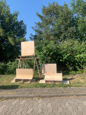 Runde Holzobjekte stehen vor gründen Holzobjekten und blauem Himmel