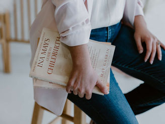 Woman sitting on stool, holding ina may gaskins books