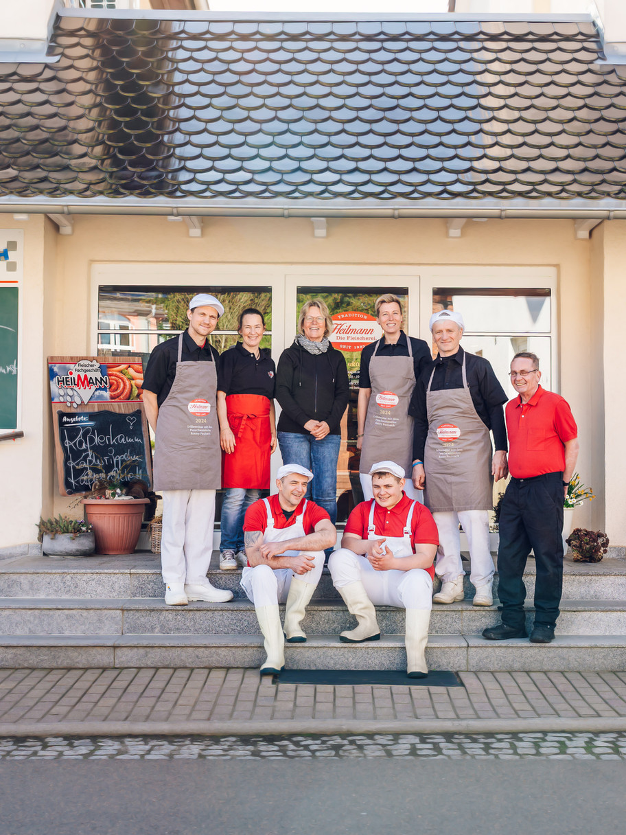 Metzgerei-Team in Arbeitskleidung vor dem Ladengeschäft