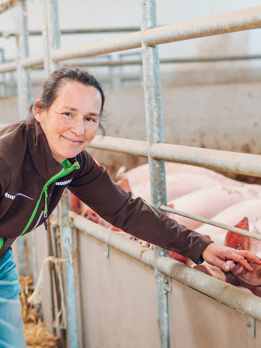 Bäuerin streichelt Schweine im Stall