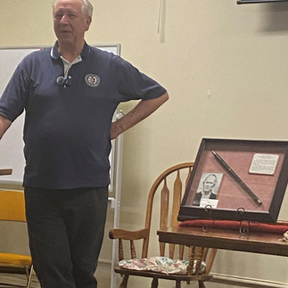 Kevin Henson presenting at the March 2025 Third Weekend Event, standing beside a Mormon Battalion fife.