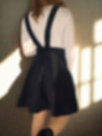 Vintage-inspired black pinafore dress with floral bib detail and shoulder straps.