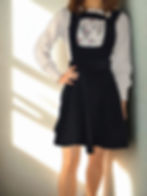 Black pinafore mini dress with a fitted waist and flared skirt, featuring a floral bib panel.