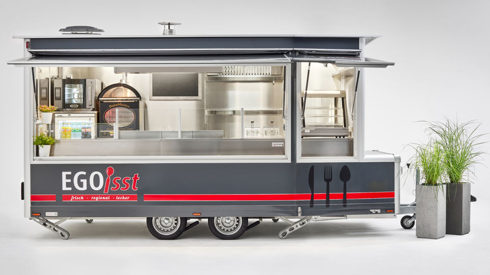 VerkaufsanhĂ€nger âEGO isst Trailerâ in Grau-Rot mit Edelstahl-Innenausstattung, 4,50âŻm LĂ€nge und 2,40âŻm Sonderbreite, komplett ausgestattet fĂŒr Imbiss und Catering â mobiler Food-Trailer mit HochleistungsgerĂ€ten und stilvollem Design.