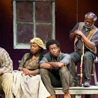 LaKesha Glover on stage in a headwrap with fellow cast members