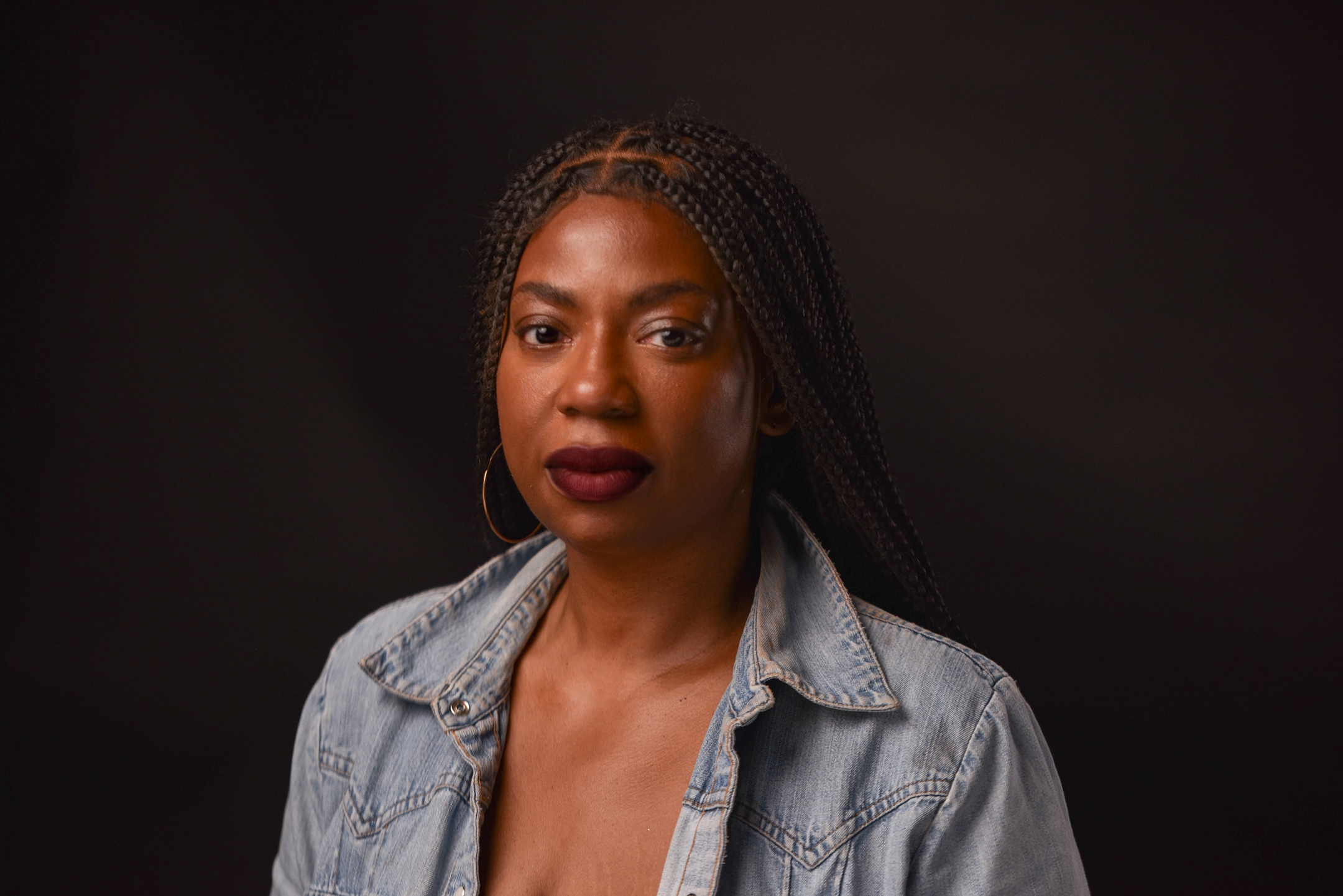 LaKesha Glover in a denim shirt against a dark backdrop