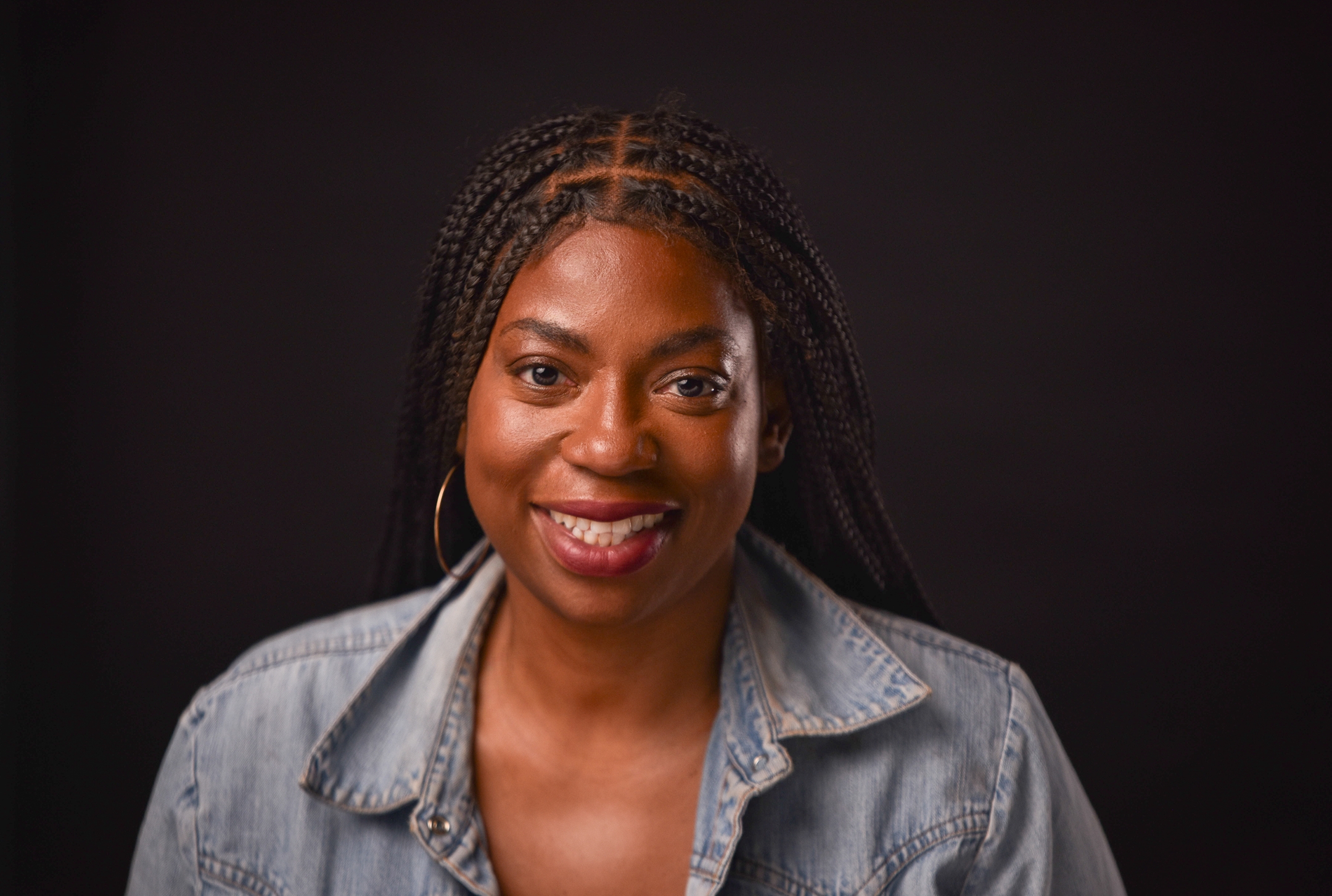 Commercial headshot of LaKesha Glover with braids in denim, smiling