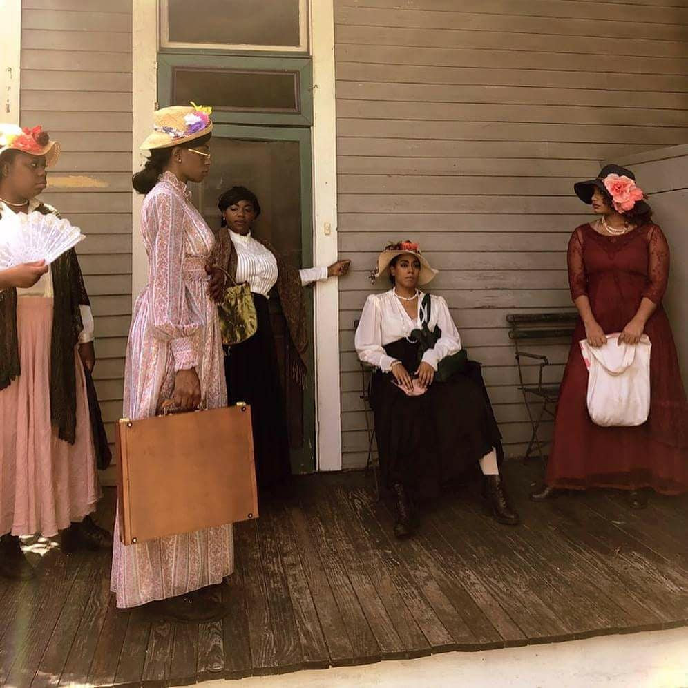 Women in period costume on a wooden porch