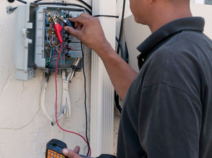 Technician tests an electrical panel with a multimeter — maintenance work order template