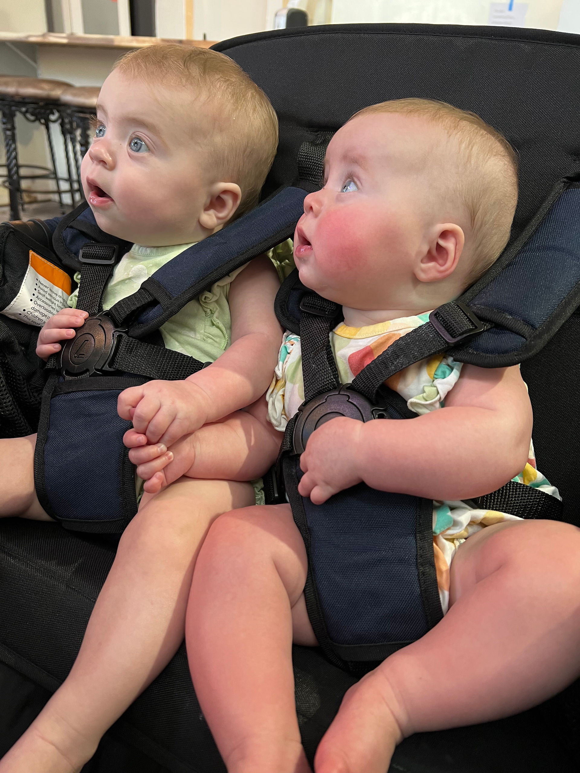 two babies sit in a wagon looking off to the side