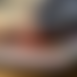 A sensory bin using a clear tub with colorful chickpeas, fidget toys, plastic tweezers, colorful blocks and alphabet letters