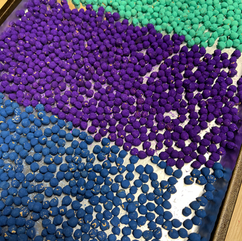 blue, purple, and teal painted chickpeas on a foil lined baking sheet