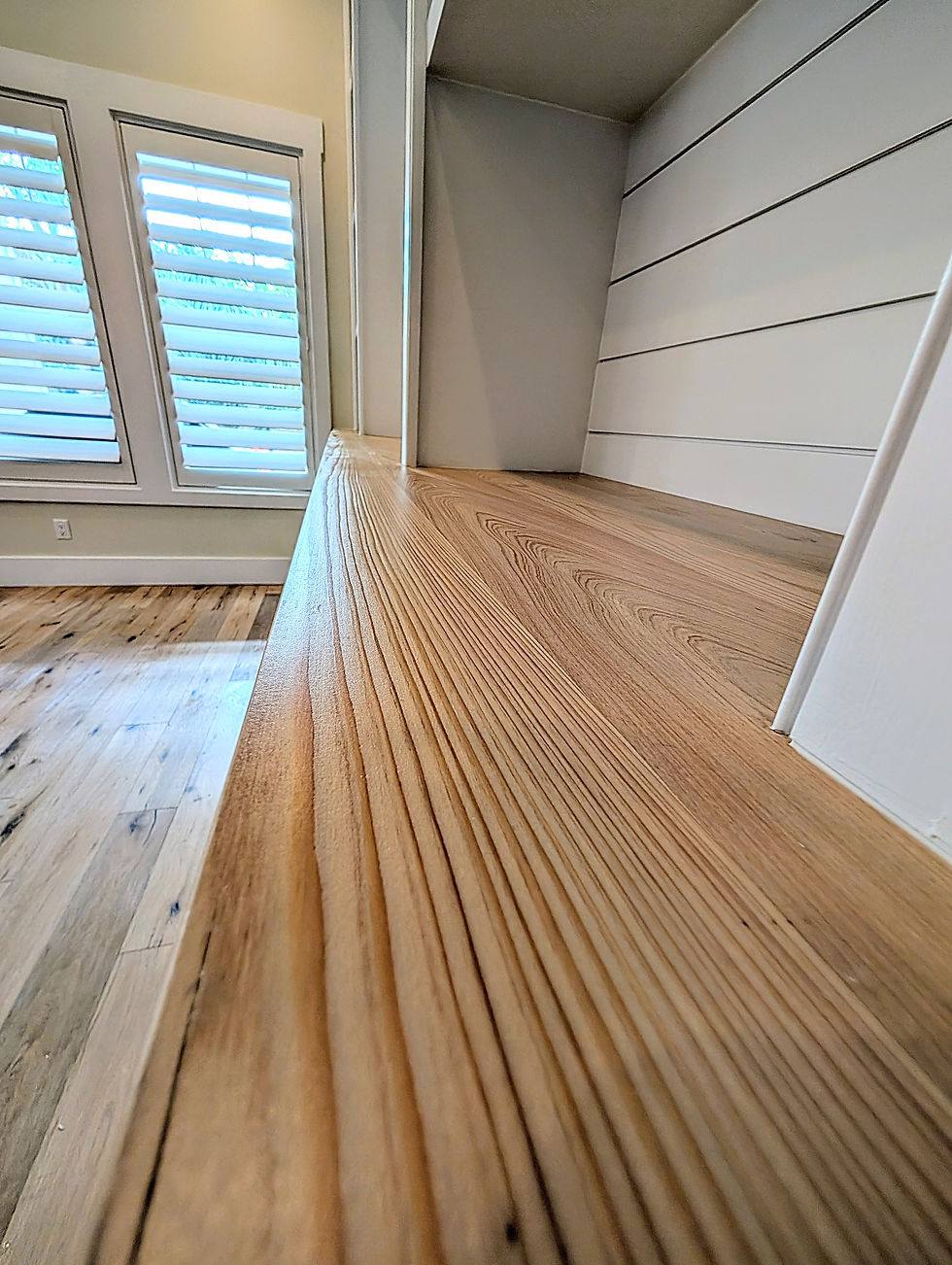 A natural wood cypress wood top in the foreground provides contrast with the crisp white shiplap cabinet back.