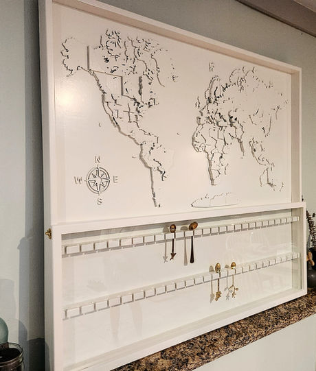 A custom relief map of the world on a large wood display wall piece that allows spoons collected around the world to hang on it to celebrate her travels.