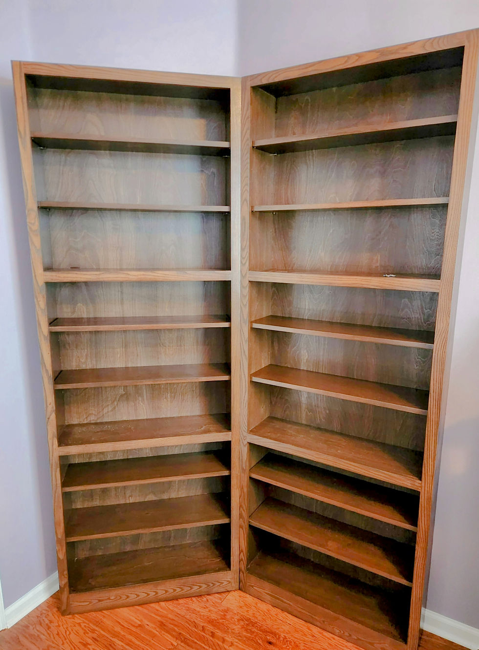 A custom wooden bookcase in classic warm stain finish fits perfectly in a corner and provides ample storage.