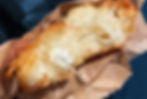 A burek, half eaten in a paper bag