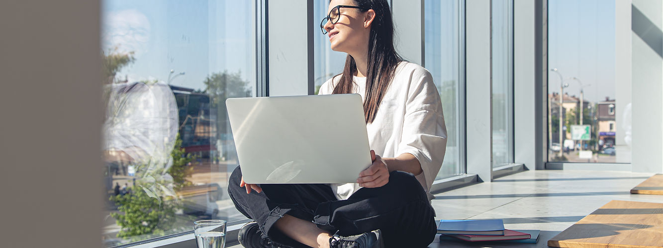 Young woman working on laptop by window