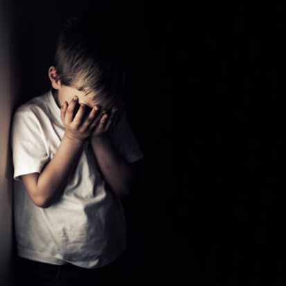 Distressed boy with hands over face