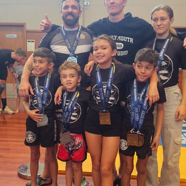 Martial arts team with medals in a gallery setting.