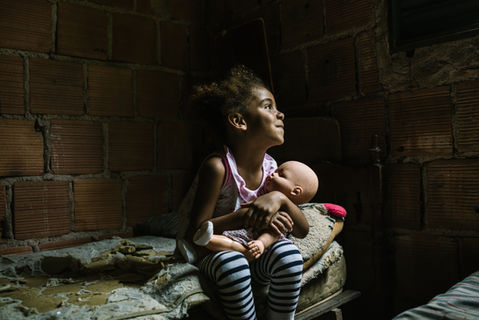 Young girl holds a doll, looking up