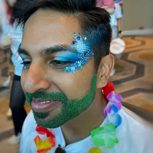 Man wears glitter makeup and face paint with green glitter beard