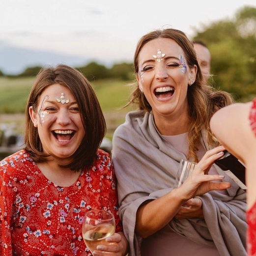 Ladies laughing wearing glitter makeup, gems and face paint 