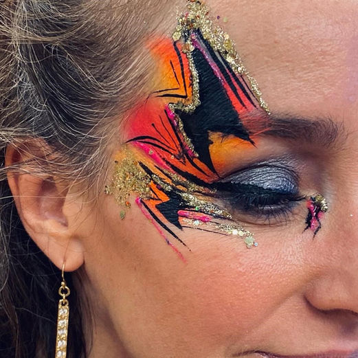Lady wears orange and pink glitter makeup and face paint 