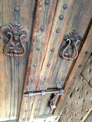 Door knockers and lock on a worn wooden door.