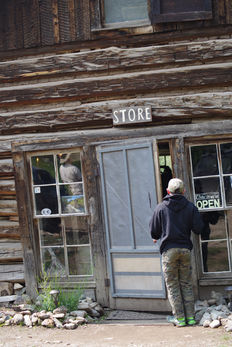 A young man peeking into the doorway of an early 20th century store.