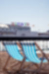Image of deck chairs with Brighton Pier in the background