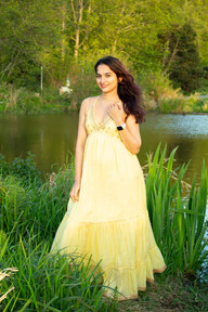Desi woman posing in front of pond by Golden Garden’s beach in a Seattle Sunset Portrait in a yellow flowing dress