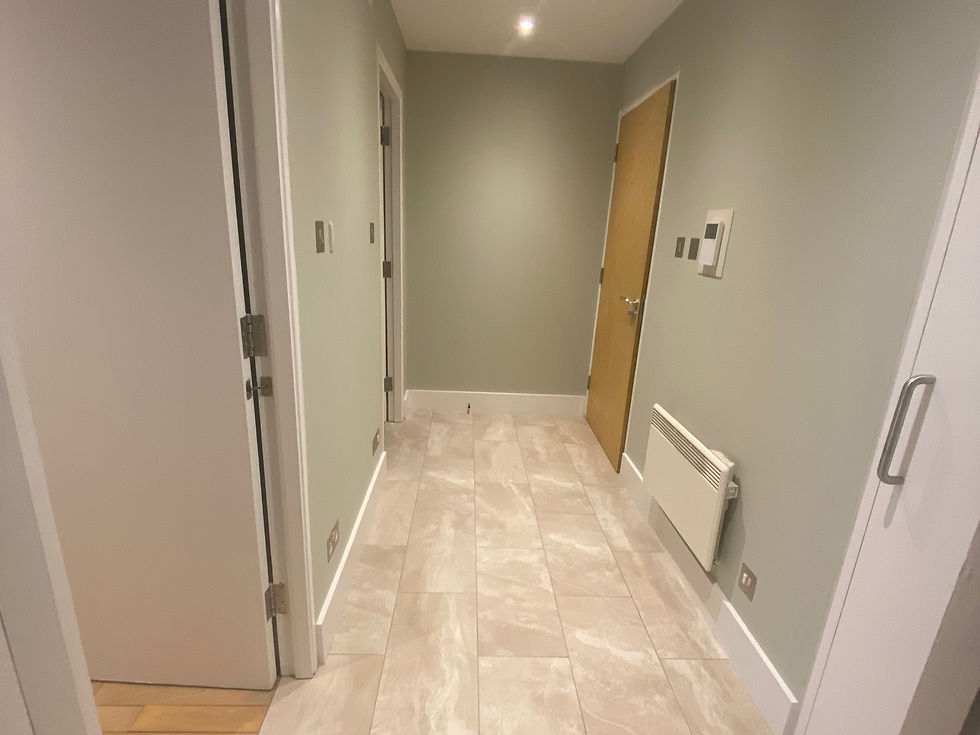 A hallway with light green walls, beige tiled floor, and multiple doors. Bright lighting with a calm, clean atmosphere.