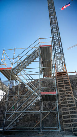 Crane bridge assembled by Leading Edge Scaffold in Henderson, Nevada, featuring tall steel girders  with extensive scaffolding, enabling crane operators to easily access current equipment on a multi-level job site. Visit LeadingEdgeScaffold.com for expert scaffolding solutions.