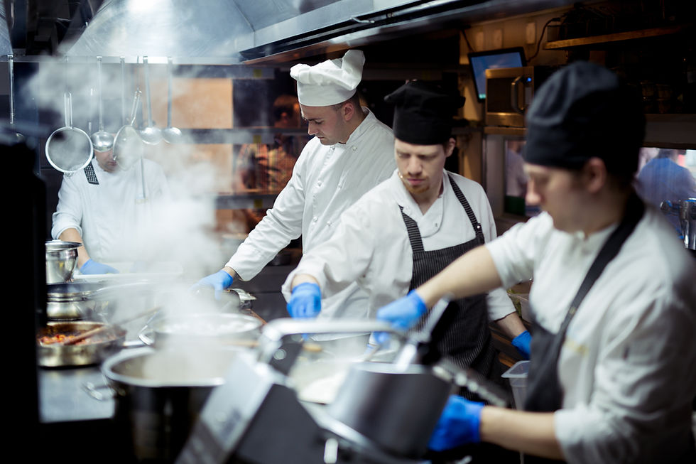 Chefs in a busy kitchen wearing white uniforms and blue gloves, cooking with pots and pans amid steam, focused and intent.