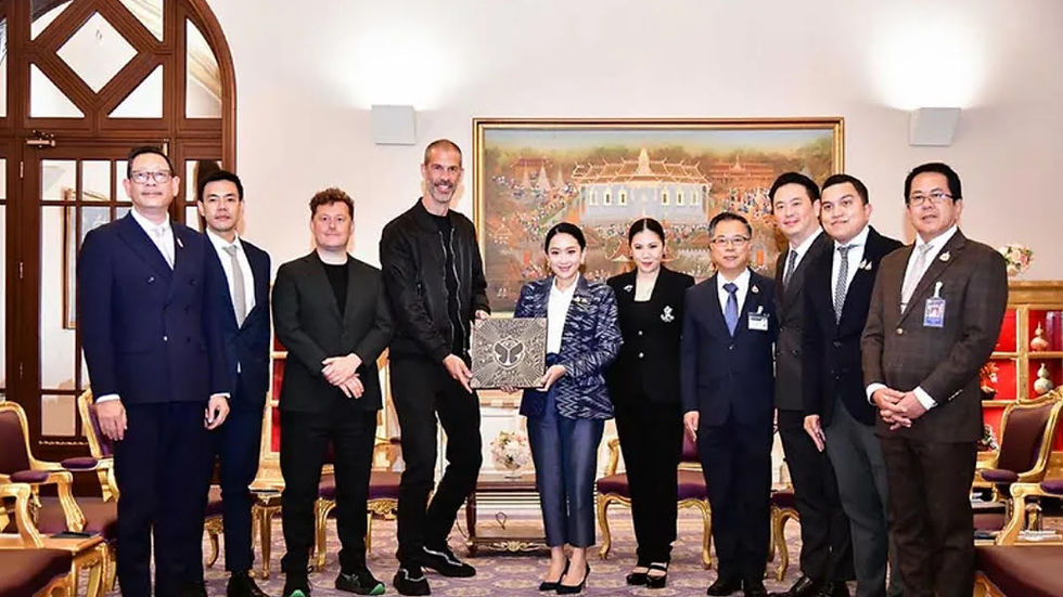 A group of 10 people in formal wear stand in a decorated room with a large painting. One holds a detailed box. The mood is formal.