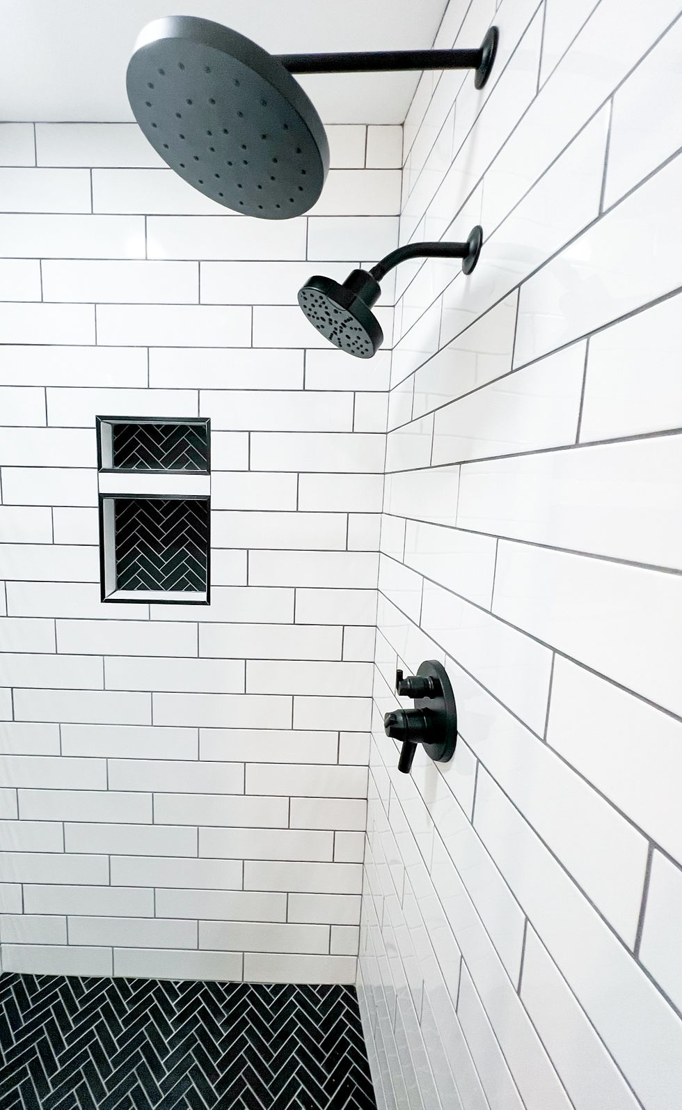 black and white bathroom, rain head shower, black fixtures, black herringbone tile, white subway tile, delta h2O Kinetic shower head,greenville south carolina contractors, husky builders, picket tile, subway tile, white tile, neutral bathroom, gold fixtures, open shower, arch shower, designer, interior designer, design and construction, construction, bathroom remodel