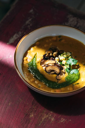 Creamy vegetable soup topped with sliced mushrooms and herbs