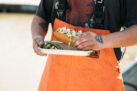 Person in orange waders holding a fresh lobster roll