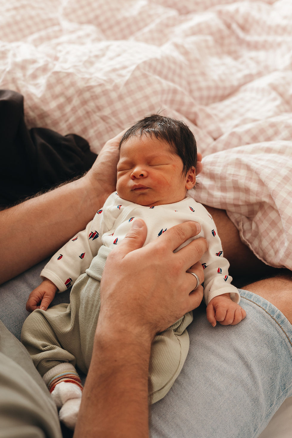 Neugeborenes Baby schläft auf dem Arm eines Elternteils im Wochenbett zuhause – liebevoller Moment der Nähe nach der Geburt in Wien