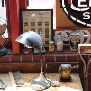 Vintage workshop scene with an industrial desk lamp, rusty fan, glass bottles, paint charts, and tools on a wooden workbench, radiating nostalgia.