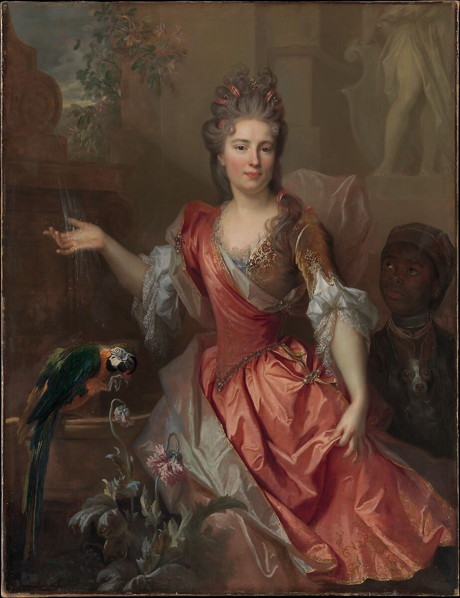 A woman in fine seventeenth-century dress stands next to a parrot and holds out her hand. To her side, partially obscured by her arm and clothing a young Black boy looks upwards towards her. She looks outwards towards the viewer.
