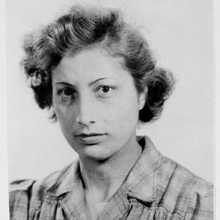 Black-and-white portrait of a young woman with short, wavy hair wearing a plaid collared shirt; she gazes calmly at the camera.