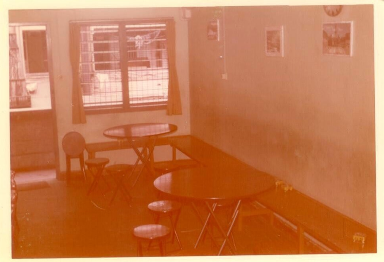 Tables and chairs in a small, sparsely decorated room. 