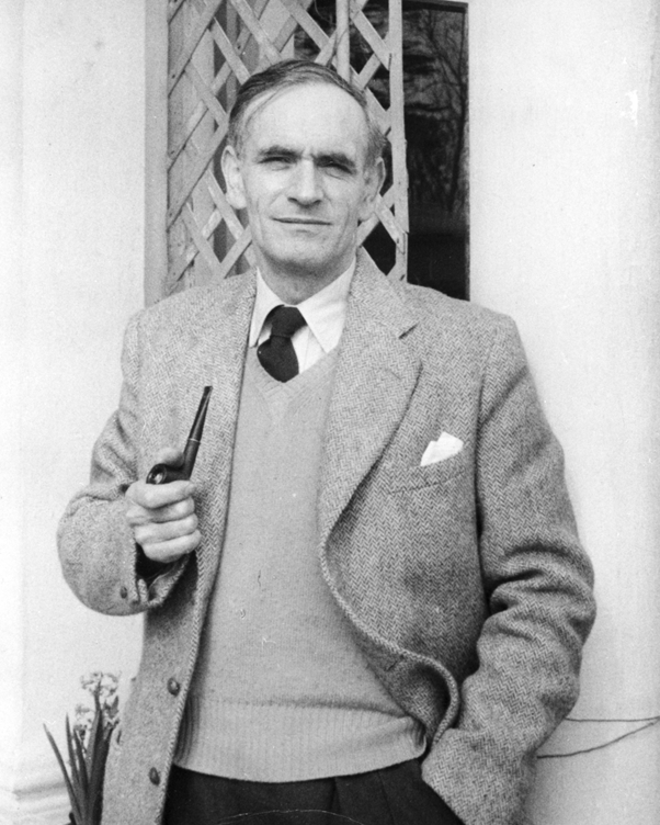 Black and white portrait of Professor Emyr Estyn Evans, standing outdoors in a suit and tie with a pipe in his right hand.