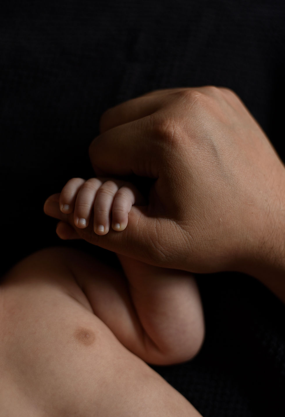 Baby holding his father's thumb.