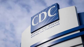 Exterior sign of the Centers for Disease Control and Prevention (CDC) headquarters, showing the blue CDC logo and full agency name against a cloudy sky.