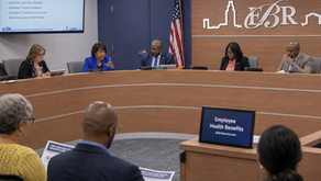 East Baton Rouge Parish School Board members seated at a curved dais during a meeting on Employee Health Benefits, with a slide listing the 2026 Medical Plan Renewal agenda visible on a wall-mounted screen.