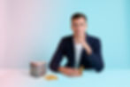Zooz founder Daniel Soos sitting at a table with 7 cans of Zooz and some orange rind against a blue/purple background